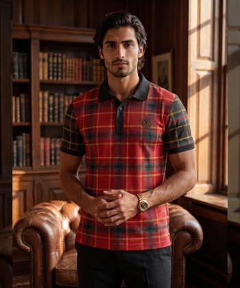 Front view of a man wearing a red, green, and black plaid polo shirt with a black collar, standing in a classic library setting.