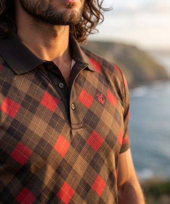 Close-up detail of the men's Charkhana polo shirt showing the breathable micro-mesh fabric texture, brown self-fabric collar, multi-button placket, and small red chest logo.