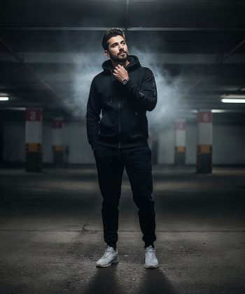 A man in a dark parking lot wearing The Phantom, a sleek black Winter Tracksuit Pakistan.