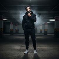 A man in a dark parking lot wearing The Phantom, a sleek black Winter Tracksuit Pakistan