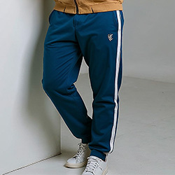 Model posing in mens navy blue track pants with side stripes