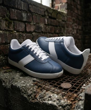 3/4 angle view of Retro Glide navy leather sneakers featuring white side panels, resting on a textured urban surface.