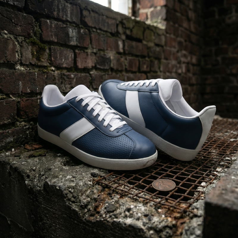 3/4 angle view of Retro Glide navy leather sneakers featuring white side panels, resting on a textured urban surface.