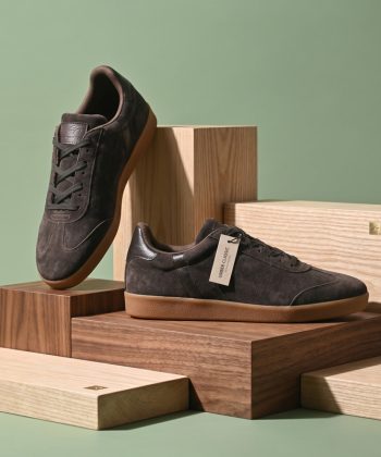 Pair of Umber Classic suede sneakers in dark brown with gum soles resting on wooden display blocks.
