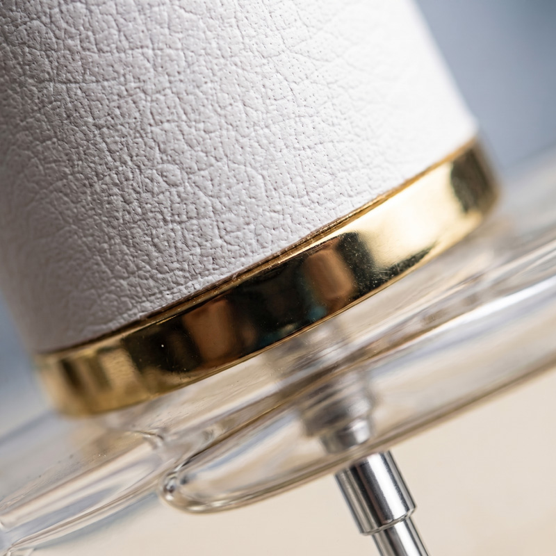 Macro photography focusing on the Reference perfume bottle's white leather-style cap, polished gold collar, and the thick glass shoulder