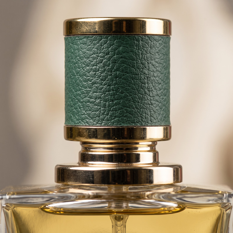 Close-up macro shot of the Moscow Perfume bottle cap, featuring a luxurious green textured leather wrap and a gold atomizer nozzle